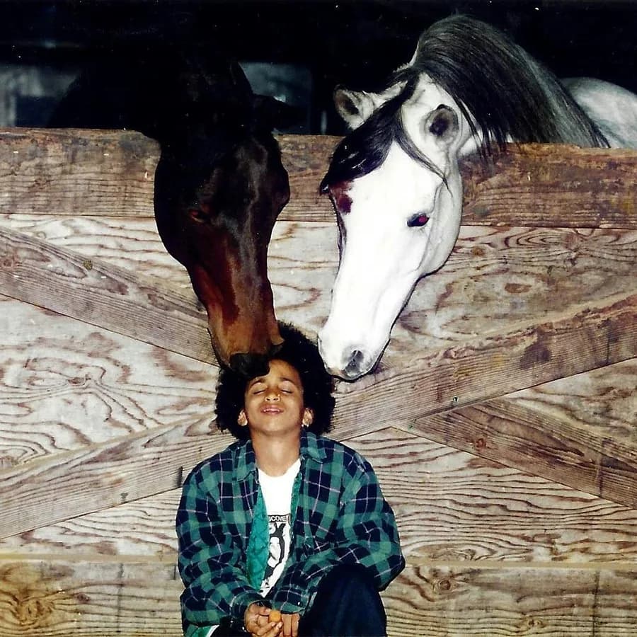 Young Jas Leverette with two horses sniffing his hair